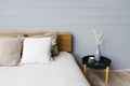 Black modern bedside table next to the double bed with grey bedding in a simple bedroom interior Royalty Free Stock Photo