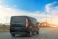 Black modern passenger charter van with a small delivery moves fast on the highway to the urban suburbs. Business distribution and Royalty Free Stock Photo