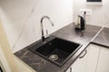 Black modern sink with water tap built into granite worktop in kitchen, industry Royalty Free Stock Photo