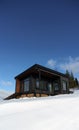 Black modern tiny cabin in snowy weather with blue clear sky