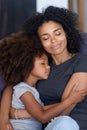 Black mom and small daughter hugging tenderly on couch