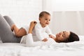 Black Mommy Playing With Baby Lying On Her Stomach Indoor Royalty Free Stock Photo