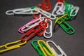 On black monophonic background plastic multi-colored paper clips   are lie. White, red, green, yellow colors. Office. Royalty Free Stock Photo