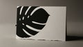 Black monstera leaf silhouette on a textured white card with torn edges Royalty Free Stock Photo