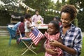 Black mother and baby holding flag at 4th July garden party