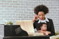 Black mother is working on the phone and raising her children together in the house. Royalty Free Stock Photo