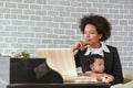 Black mother is working on the phone and raising her children together in the house. Royalty Free Stock Photo