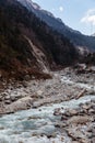 Black mountain with snow on the top. On the ground is frozen river with white stone and ice at Thangu and Chopta valley in winter. Royalty Free Stock Photo