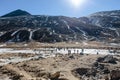 Black mountain witn snow and below with tourists on the ground with brown grass, snow and frozen pond in winter at Zero Point. Royalty Free Stock Photo