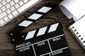 Black movie clapper with keyboard and script sheets on a wooden table