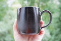 Black mug made of clay. decor - covering with black engobe and transparent glaze. two firing. made on a potter`s wheel. handmade