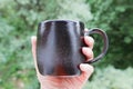 Black mug made of clay. decor - covering with black engobe and transparent glaze. two firing. made on a potter`s wheel. handmade