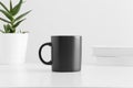 Black mug mockup with a aloe vera in a pot and books on a white table Royalty Free Stock Photo