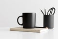 Black mug mockup with workspace accessories on a white table