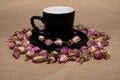 A black mug with a saucer with tea made from dried buds and petals of a purple damask rose stands on a paper background Royalty Free Stock Photo