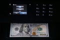 Black multifunction printer with touch screen display makes copy of 100 dollar bill in the dark. Money machine.