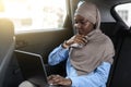 Black muslim businesswoman working on laptop while going by car to office Royalty Free Stock Photo