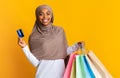 Black muslim girl in headscarf holding credit card and shopping bags Royalty Free Stock Photo