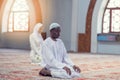 Black Muslim man and woman praying in mosque