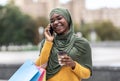 Black Muslim Woman With Shopping Bags And Coffee Talking On Cellphone Outdoors Royalty Free Stock Photo