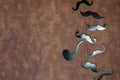 Black mustache and hat on brown leather background texture with copy space, International Men's day and Fathers Day concept