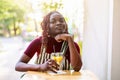 Black non-binary person sitting in an outdoor cafe