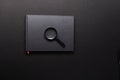 Black notebook and magnifying glass. Magnifying glass on a notebook. Search for information. Black Internet. Royalty Free Stock Photo