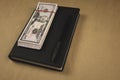A black notebook , a pen and dollar cash banknotes on wooden background - concept of financial management or planning, make money