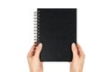 Black notebook for writing or drawing on spiral in hand, isolated on white background Royalty Free Stock Photo