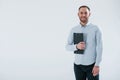 Black notepad in hands. Man in official clothes stands against white background in the studio Royalty Free Stock Photo