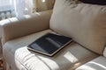 Black notepad with spiral binding on beige couch in cozy, sunlit room. Writing, journaling and relaxation