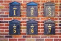 Black numbered mailboxes on brick wall at apartment building