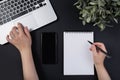 Black office desk with laptop and white mockup notepad