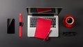 Black office desk table with blank screen laptop computer, notebook, watch, mobile phone and red cup of coffee Royalty Free Stock Photo