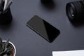 Black office desk table with blank smartphone surounded by camera lens Royalty Free Stock Photo