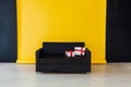 Office sofa with red gifts in the interior of the room with a yellow background Royalty Free Stock Photo