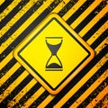 Black Old hourglass with flowing sand icon isolated on yellow background. Sand clock sign. Business and time management Royalty Free Stock Photo
