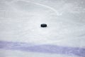 Black, old ice hockey puck on ice rink ice near blue line Royalty Free Stock Photo