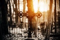 A black old patterned cross stands on a stone tombstone in the middle of the cemetery, surrounded by a dark forest, illuminated by Royalty Free Stock Photo