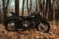 Black old russian motorbike K 750 in autumn wood.