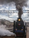 Black old Soviet steam locomotive with smoke and steam departs from the station