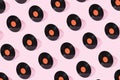 Black old vinyl record with orange clean label isolated on pastel pink background. Creative retro music pattern concept.