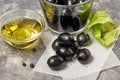Black olives, glass bowl with oil on background.
