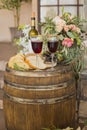 Black olives in glass vase, bread and vine, flowers on old oak barrel Royalty Free Stock Photo