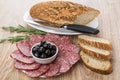 Black olives and pieces of sausage, bread, rosemary and knife Royalty Free Stock Photo