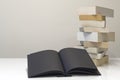 Black open book in foreground of pile of books Royalty Free Stock Photo