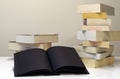 Black open book in foreground of two piles of books Royalty Free Stock Photo