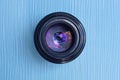 Black open camera lens lies on a blue table