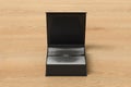 Black opened square folding gift box mock up with silver wrapping paper on wooden background. Front view