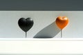 Black and orange heart shapes with cast shadows on a clean, white surface. Minimalist and symbolic design.
